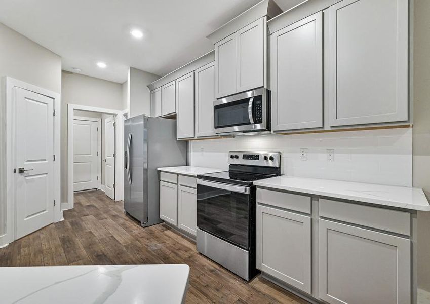 Grey cabinets, quartz countertops and stainless steel appliances fill the home's kitchen.