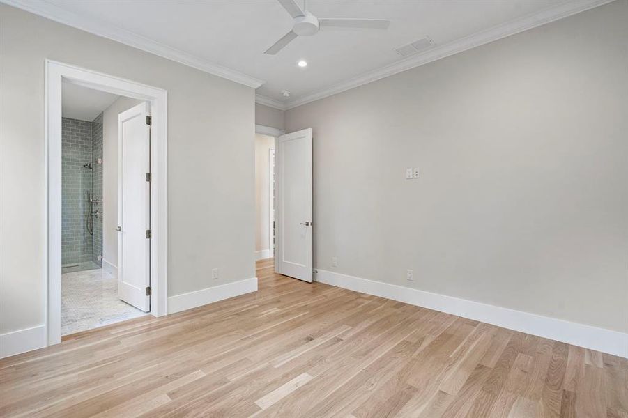 Unfurnished bedroom with light wood-type flooring, ceiling fan, connected bathroom, and ornamental molding