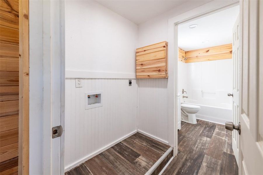 Dedicated laundry area featuring beadboard wainscoting and wood-finish flooring