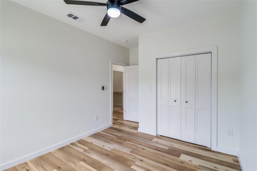 Unfurnished bedroom featuring baseboards, visible vents, light wood-style floors, a closet, and ceiling fan