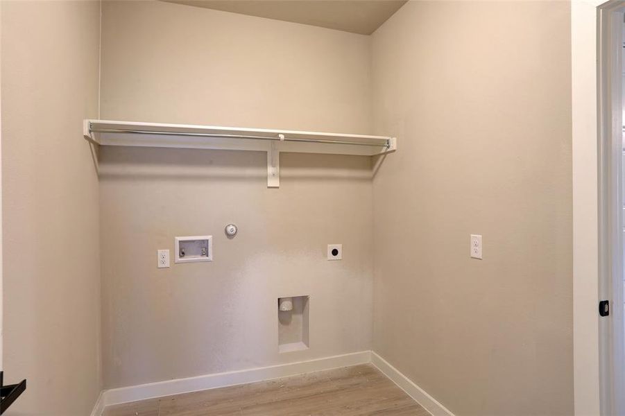 Laundry room with hookup for a gas dryer, light wood finished floors, hookup for an electric dryer, and hookup for a washing machine Laundry room with hookup for a gas dryer, light wood finished floors, hookup for an electric dryer, and hookup for a washing machine