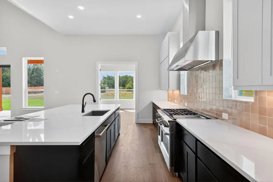 Kitchen with dark cabinetry, dark wood-type flooring, light stone countertops, recessed lighting, and white cabinets Kitchen with dark cabinetry, dark wood-type flooring, light stone countertops, recessed lighting, and white cabinets