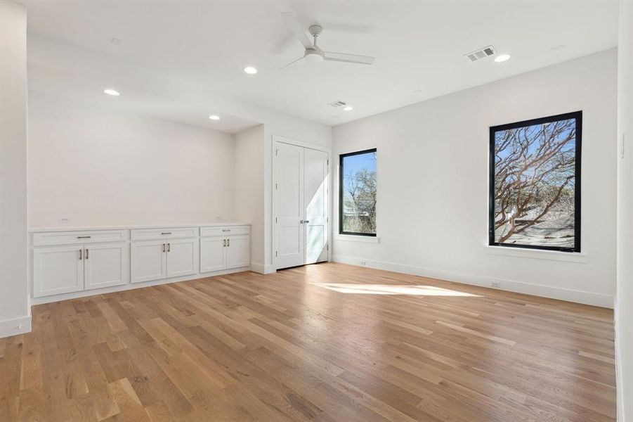 Game room with light wood built in cabinets, closet and ceiling fan