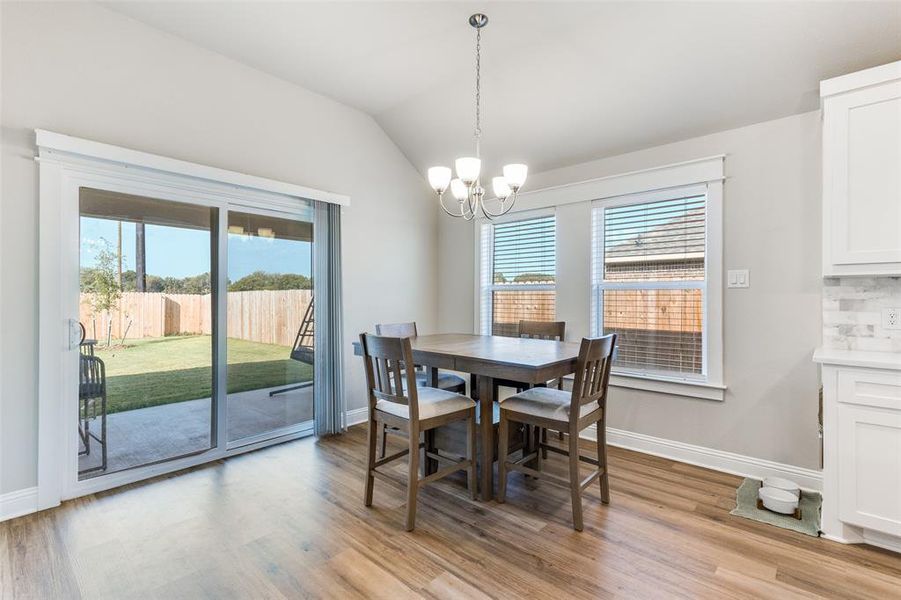 Dining space featuring light wood-style flooring, vaulted ceiling, and a chandelier Dining space featuring light wood-style flooring, vaulted ceiling, and a chandelier