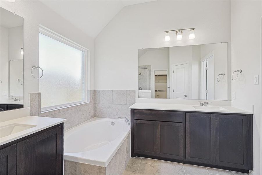 Bathroom featuring tile patterned floors, vanity, vaulted ceiling, and shower with separate bathtub