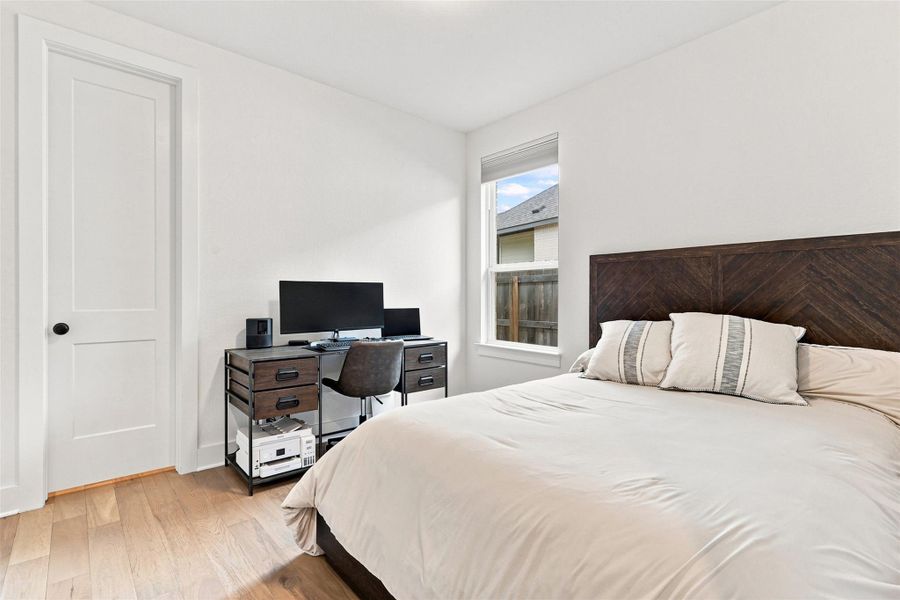 Gleaming hardwood floors and a tall window bring warmth to this versatile secondary bedroom.