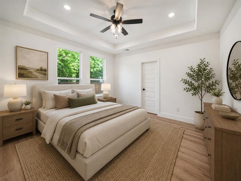 Spacious bedroom with a tray ceiling, recessed lighting, and a ceiling fan Spacious bedroom with a tray ceiling, recessed lighting, and a ceiling fan