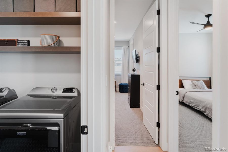 Not to be overlooked, the notable upstairs laundry room matches the stylish design of the rest of the home and has been cleverly outfitted with a state of the art washer and dryer, black penny floor tiles, custom cabinets, open wood shelving, a useful sink, and expansive folding space.