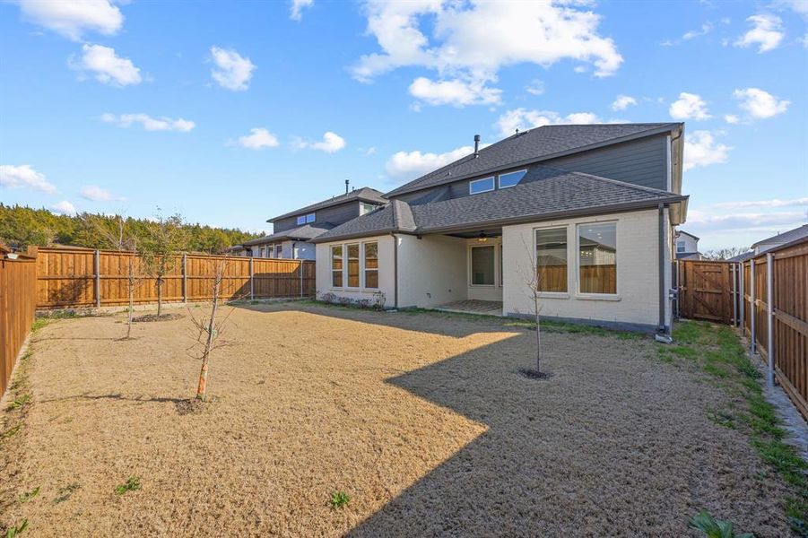 Back of property with a patio area, a fenced backyard, roof with shingles, brick siding, and a gate