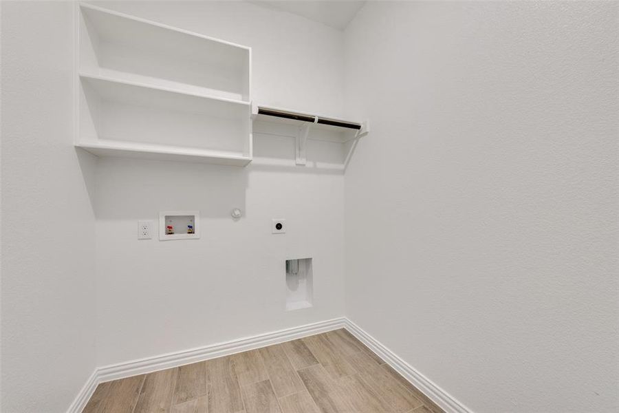 Washroom featuring hookup for an electric dryer, light wood-type flooring, hookup for a washing machine, and hookup for a gas dryer