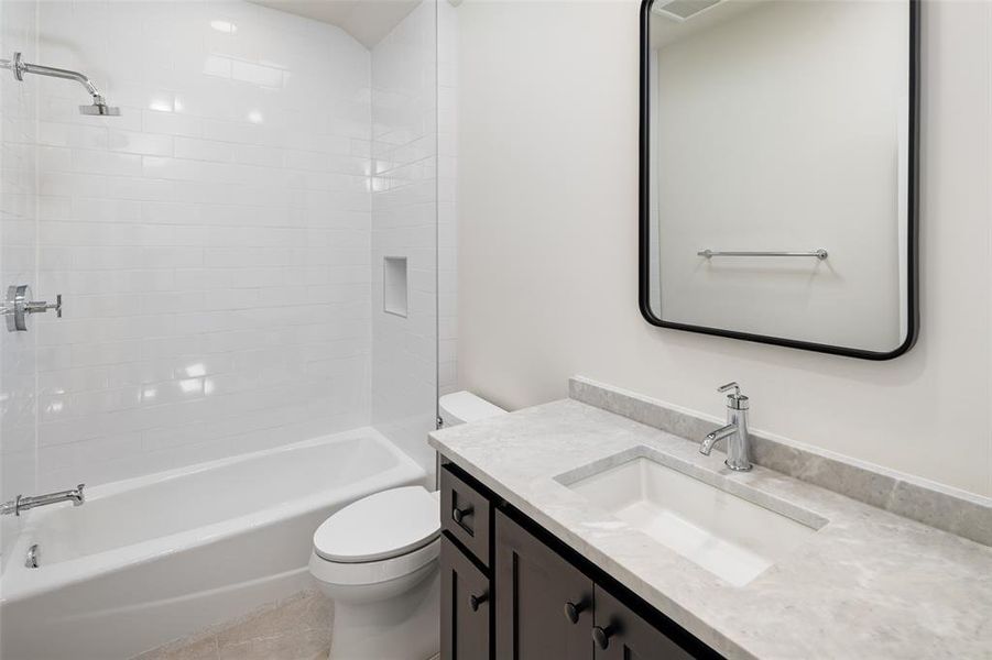 Full bathroom featuring vanity, tiled shower / bath combo, and toilet