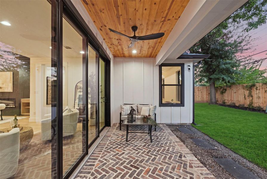 Herringbone brick detailing continues onto the rear patio, creating a seamless connection between the front and backyard design.