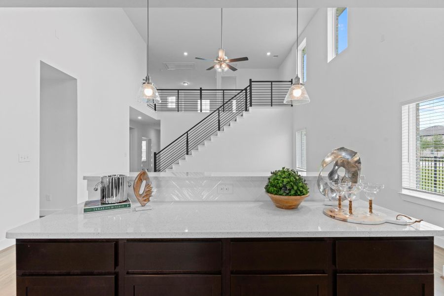 A beautiful view from the kitchen island highlights the soaring ceilings, open staircase, and spacious living area beyond—combining elegance with everyday functionality. **Image Representative of Plan Only and May Vary as Built**. A beautiful view from the kitchen island highlights the soaring ceilings, open staircase, and spacious living area beyond—combining elegance with everyday functionality. **Image Representative of Plan Only and May Vary as Built**.