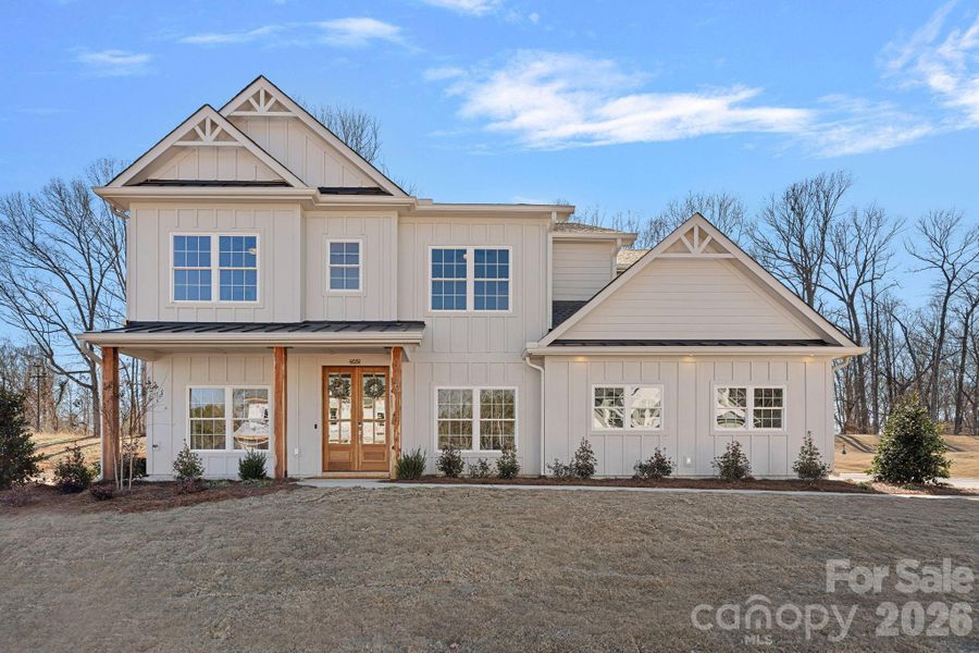 Classic curb appeal with board-and-batten siding, metal roof accents, and a welcoming front porch framed by 8x8 rough sawn cedar columns on this custom ENERGY STAR home built by Shea Builders!