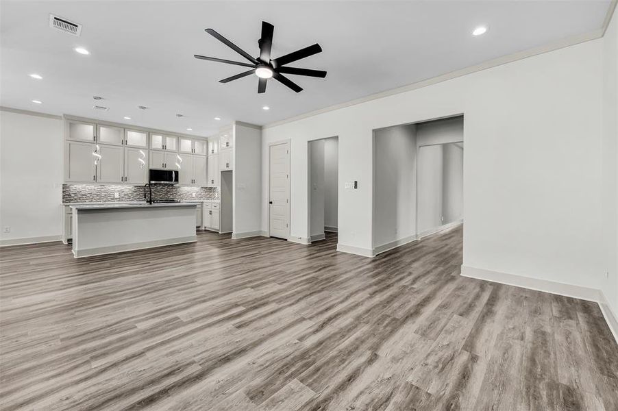 Unfurnished living room with light wood finished floors, crown molding, recessed lighting, and a ceiling fan