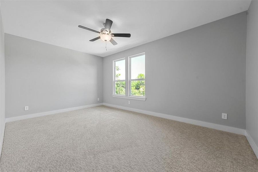 Carpeted spare room featuring ceiling fan