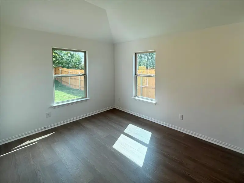 Spare room with vaulted ceiling and dark wood-style floors Spare room with vaulted ceiling and dark wood-style floors
