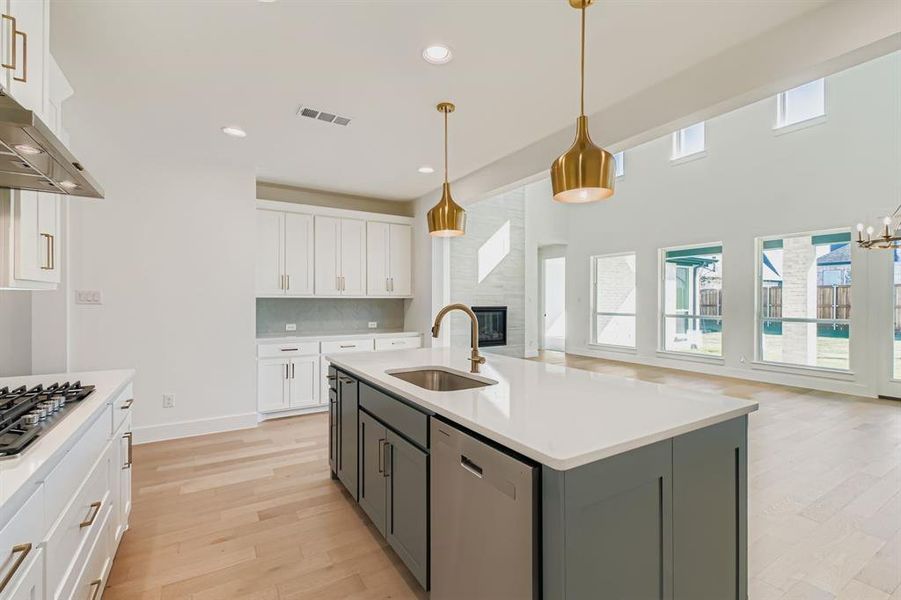 Kitchen featuring white cabinets, decorative light fixtures, appliances with stainless steel finishes, light wood-style flooring, and recessed lighting