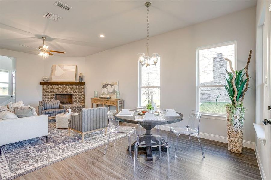 Dining room with wood finished floors, a brick fireplace, ceiling fan, plenty of natural light, and recessed lighting