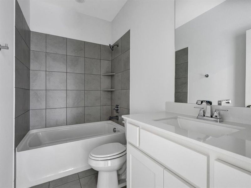 Full bathroom featuring tile patterned flooring, toilet, vanity, and tiled shower / bath