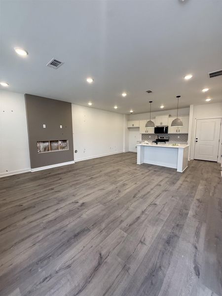 Unfurnished living room featuring dark wood-style flooring and recessed lighting