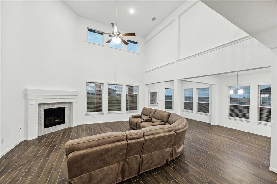 Enjoy another perspective of this light-filled, two-story family room, showcasing extensive windows that invite the outdoors in. The abundance of natural light enhances the airy atmosphere, creating a bright and inviting space perfect for relaxation, entertaining, or family fun!