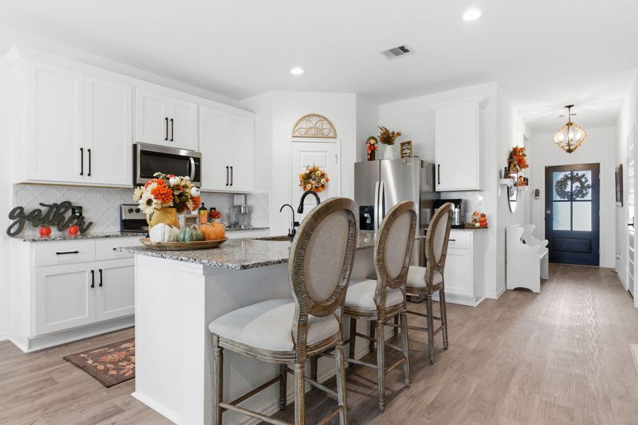 Gourmet kitchen featuring recently upgraded backsplash, granite countertops, stainless steel appliances, and a large eat-in island. Gourmet kitchen featuring recently upgraded backsplash, granite countertops, stainless steel appliances, and a large eat-in island.