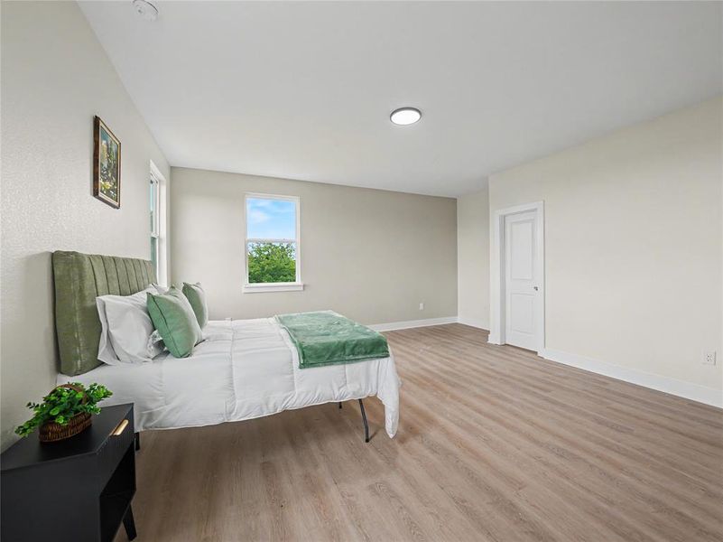 Spacious room featuring wood-finish flooring, light-toned walls, and a recessed ceiling light