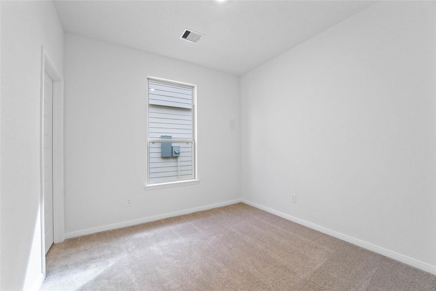Secondary bedroom, pictured here, features plush carpeting, neutral paint tones, recessed lighting, a large window, and a walk-in closet.