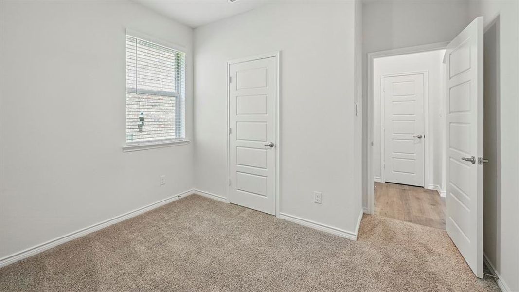 Carpeted room featuring a single window with blinds, white trim, and a white interior door with horizontal paneling