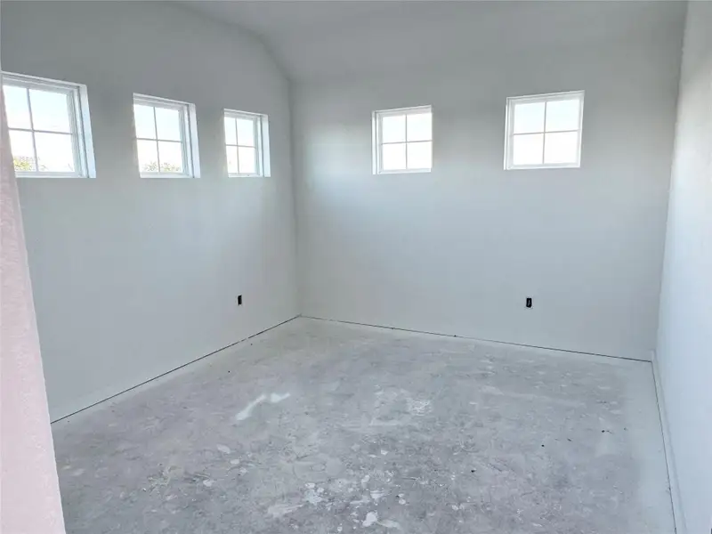 Empty room with lofted ceiling and unfinished concrete floors