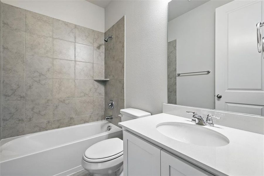 Bathroom with bathtub / shower combination, vanity, and a textured wall