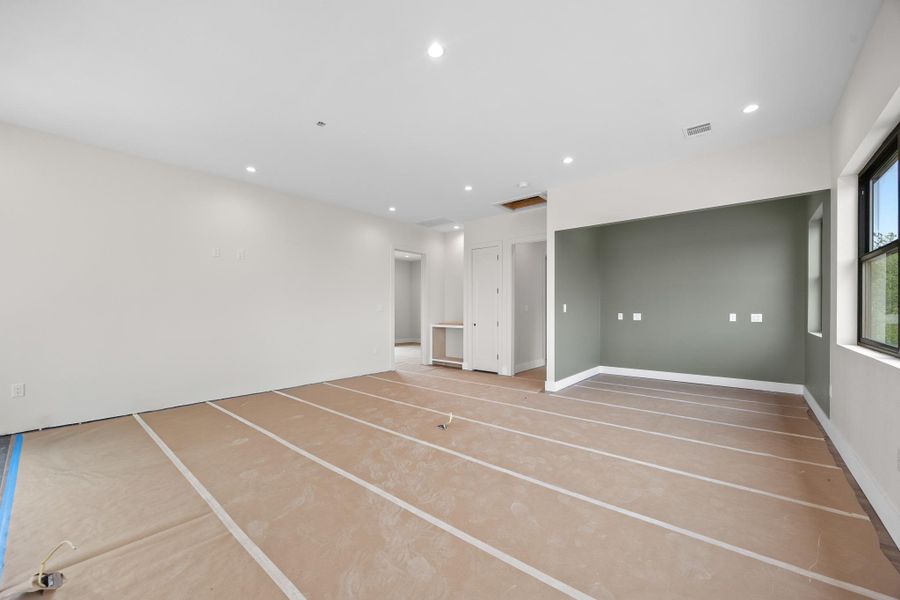 Spacious room featuring recessed lighting, a neutral color palette, dark window frames, and ample natural light