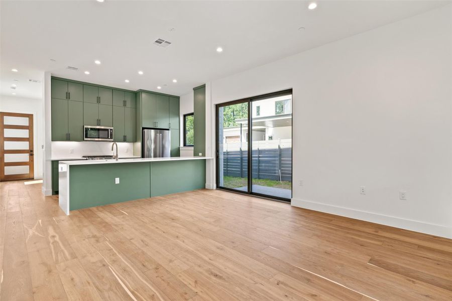 Kitchen featuring green cabinetry, light wood-style floors, light countertops, recessed lighting, and stainless steel appliances