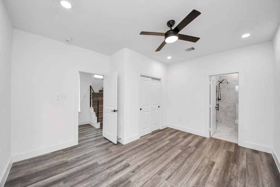 This room features modern wood flooring, recessed lighting, and a ceiling fan. It has access to a marble-tiled bathroom and a staircase, creating a sleek and functional space. This room features modern wood flooring, recessed lighting, and a ceiling fan. It has access to a marble-tiled bathroom and a staircase, creating a sleek and functional space.