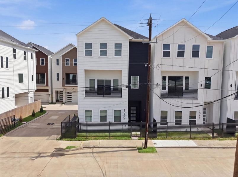 Modern three-story townhome with clean contemporary façade, private fenced front yard, and balcony, ideally situated in a stylish urban community.