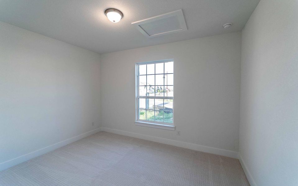 Empty room featuring light colored carpet and attic access