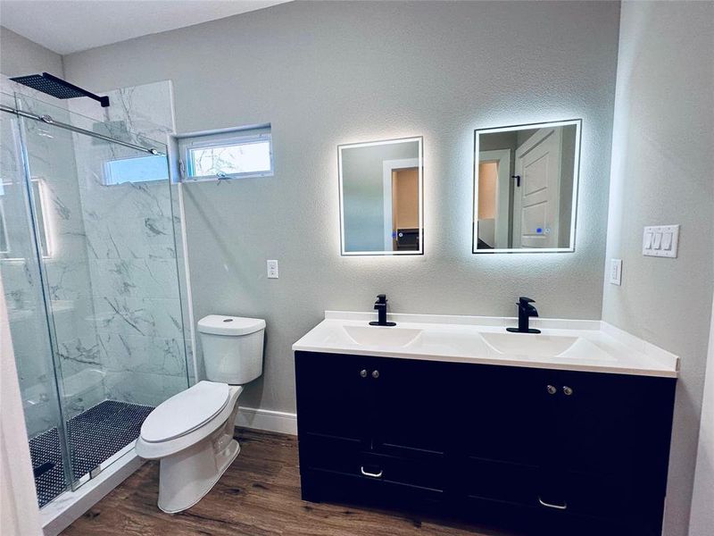 Primary bathroom with double vanity, a shower with glass door, individual mirrors with LED lights, anti-fog, and adjustable brightness.