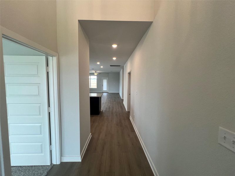 A long, inviting hallway with recessed lighting leads to an open-concept living area.