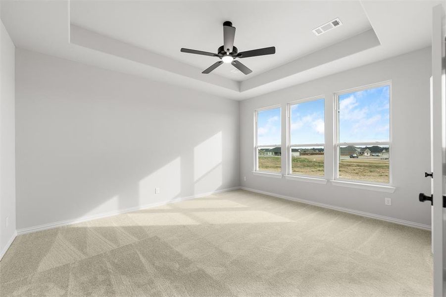 Spare room with a raised ceiling, light colored carpet, and ceiling fan Spare room with a raised ceiling, light colored carpet, and ceiling fan