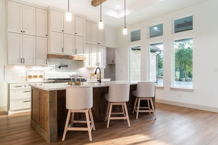 Kitchen featuring decorative backsplash, light wood finished floors, a kitchen island with sink, white cabinetry, and recessed lighting Kitchen featuring decorative backsplash, light wood finished floors, a kitchen island with sink, white cabinetry, and recessed lighting