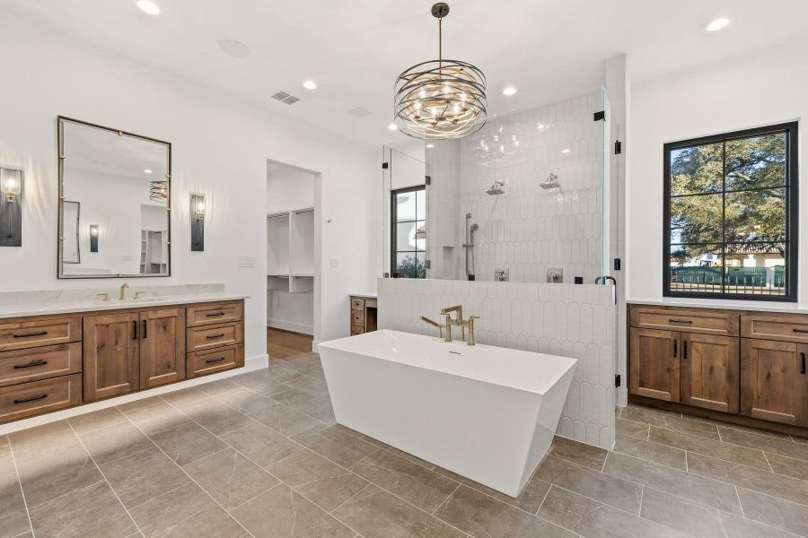 Full bath with vanity, a soaking tub, a spacious closet, a tile shower, and suspended lighting