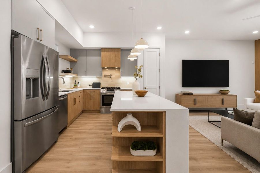 Anchored by a trio of sculptural pendants, the waterfall island incorporates open shelving that creates moments of display within the kitchen's clean framework.