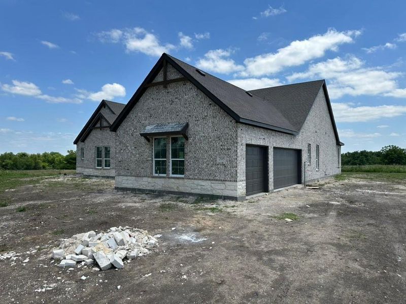 Contemporary brick exterior with stone accents, featuring a prominent gable roofline and dark shingle roofing