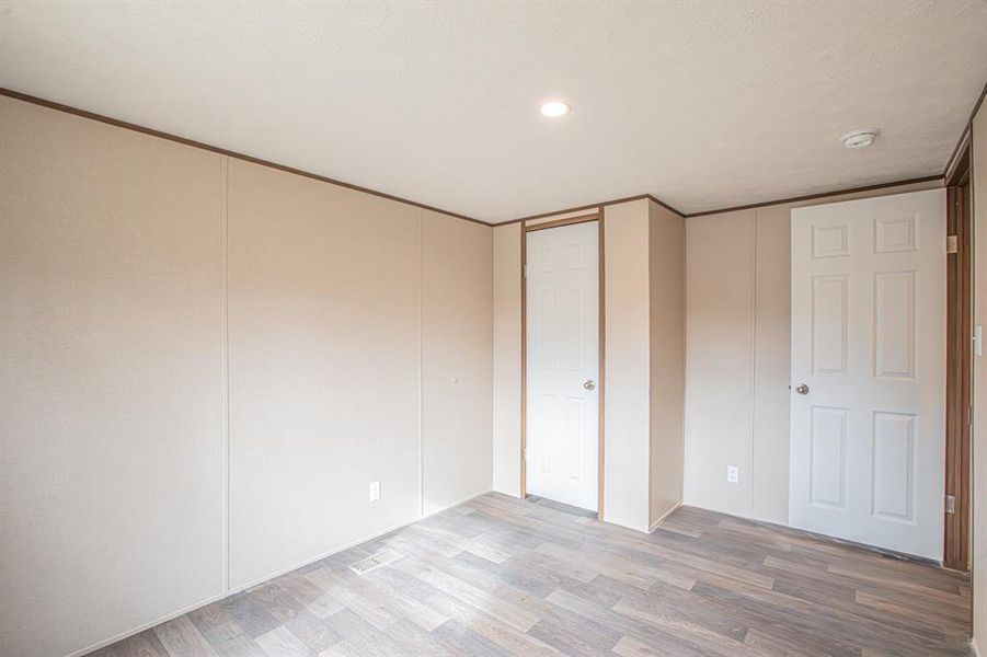 Unfurnished bedroom with light wood finished floors and recessed lighting Unfurnished bedroom with light wood finished floors and recessed lighting