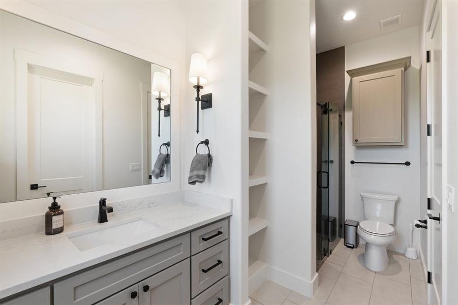 Bathroom with tile floors, built in features, vanity, and toilet