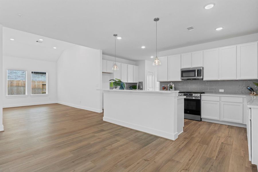 Open-concept kitchen showcases seamless flow into the adjacent dining and living areas, highlighted by pendant lighting, a spacious center island, and a clean, modern aesthetic—ideal for everyday living and entertaining. **Image Representative of Plan Only and May Vary as Built**.