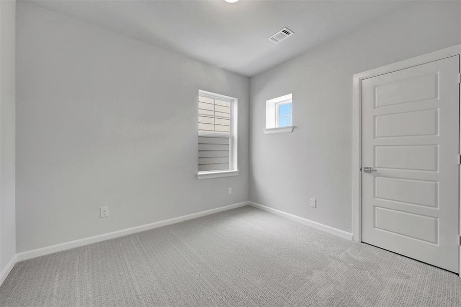 Light-filled room featuring carpet flooring, two windows, and a five-panel interior door