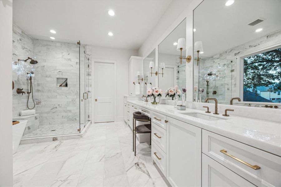 Modern and elegantly designed bathroom with a marble theme, featuring a spacious walk-in shower, a double vanity with ample storage, and sophisticated fixtures.