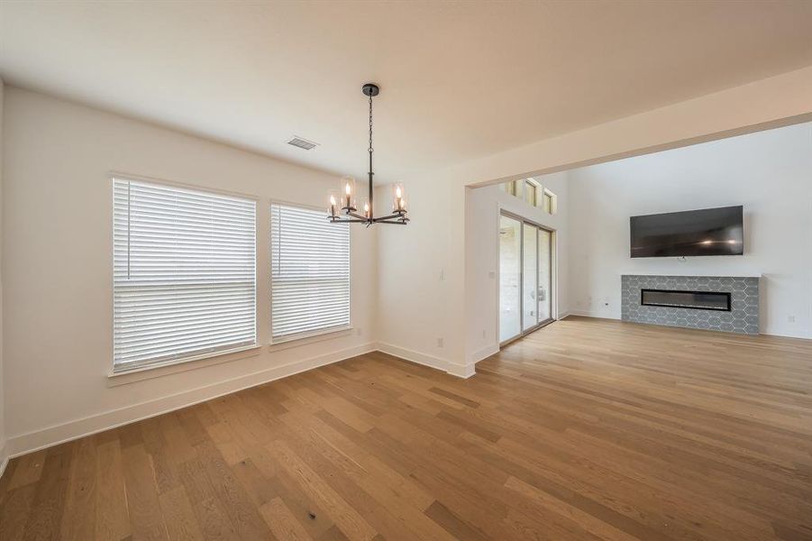 Living space featuring hardwood flooring, a modern chandelier, and two windows with blinds